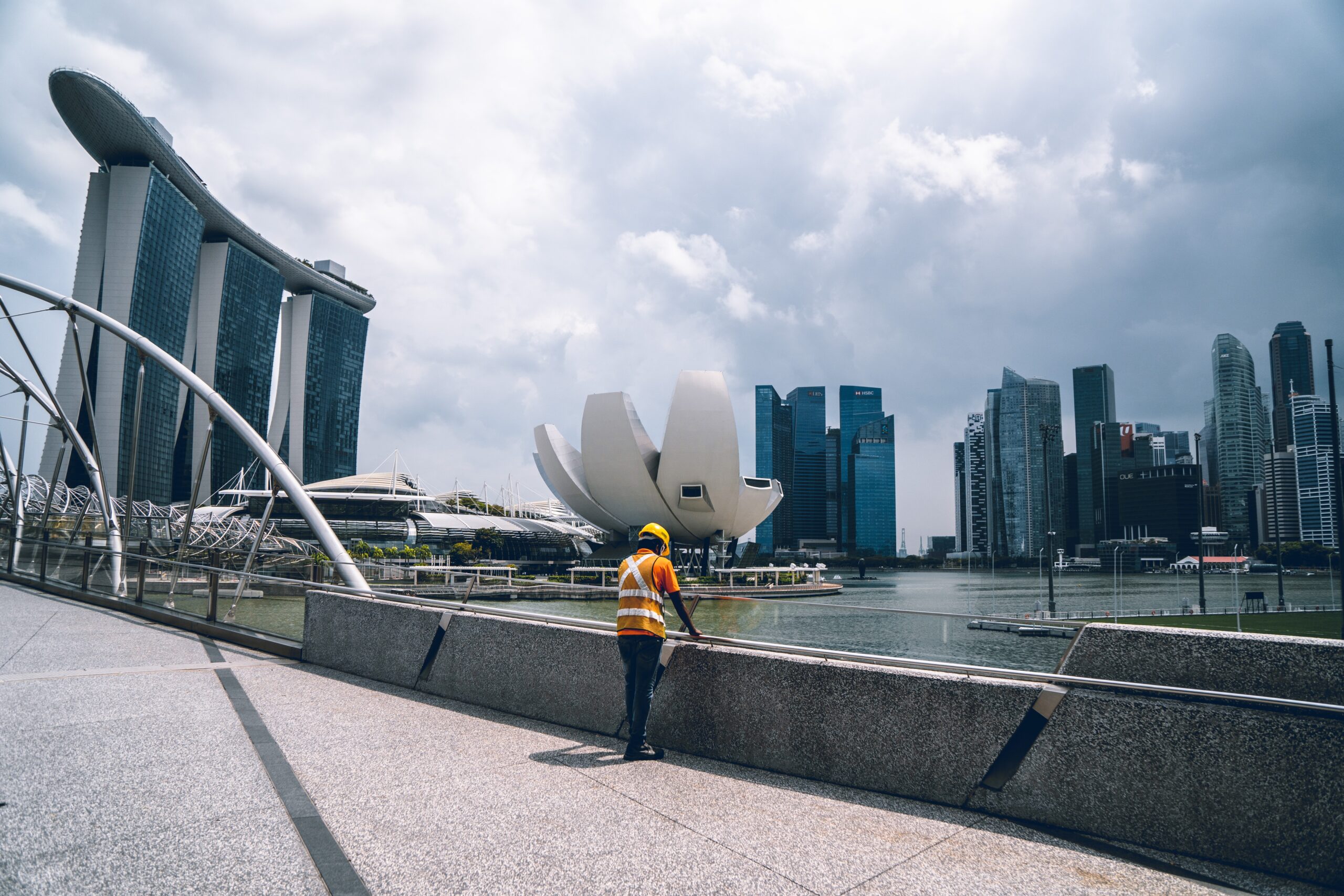 Figure wearing yellow high vis jacket in front of modern architecture