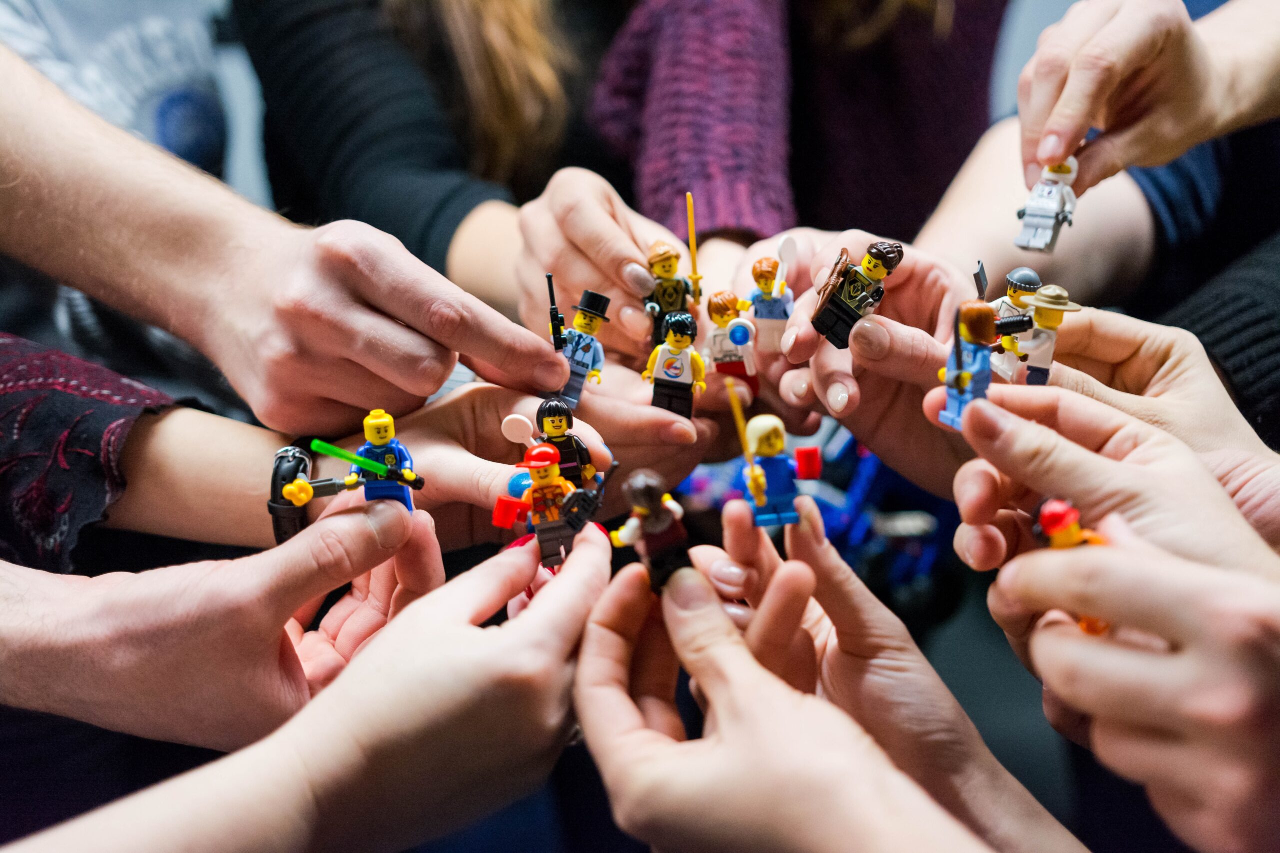 Group of hands holding Lego mini figures