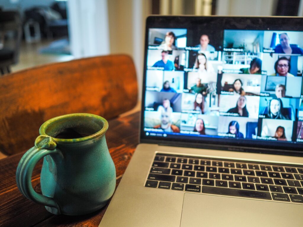 Laptop showing online meeting next to a coffee cup