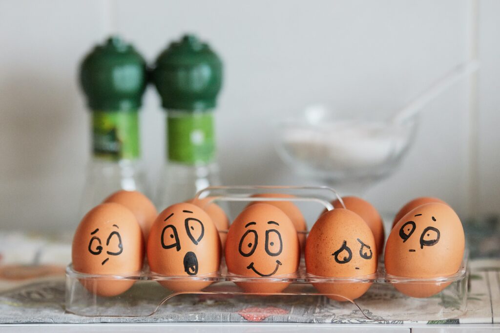 Five eggs in a row with faces drawn on expressing emotions such as happy, confused, sad, shocked