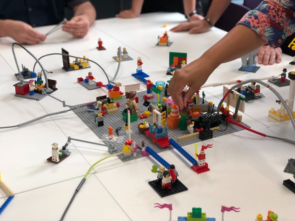 Lego scene with minifigures and people's hand
