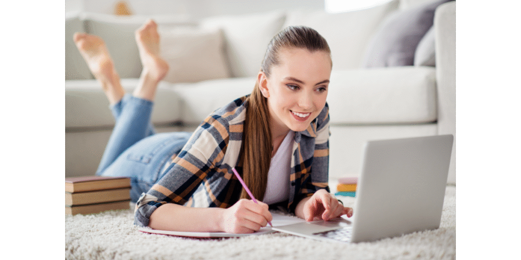 Female student lay on the floor looking relaxed in from of her laptop