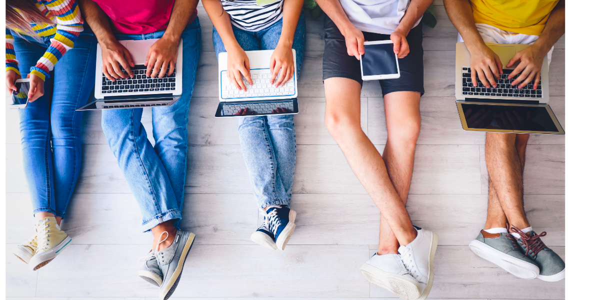 Five pairs of young people's legs wearing shorts or jeans. Each person has a laptop or tablet on their knee.